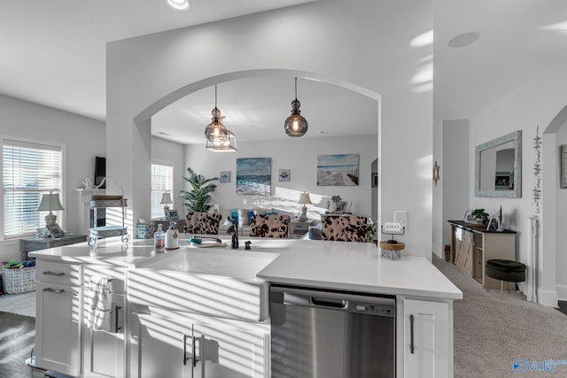 kitchen featuring arched walkways, dishwasher, light countertops, white cabinetry, and pendant lighting