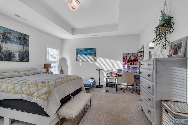 bedroom with a raised ceiling, light carpet, and visible vents