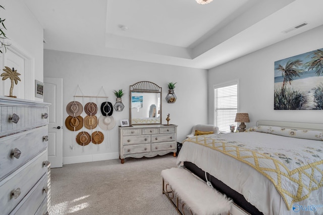 carpeted bedroom featuring a raised ceiling, visible vents, and baseboards