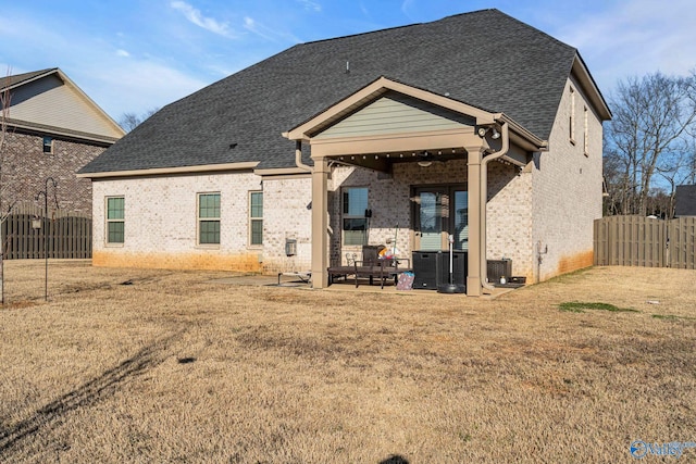 rear view of property featuring roof with shingles, fence, a patio, and brick siding