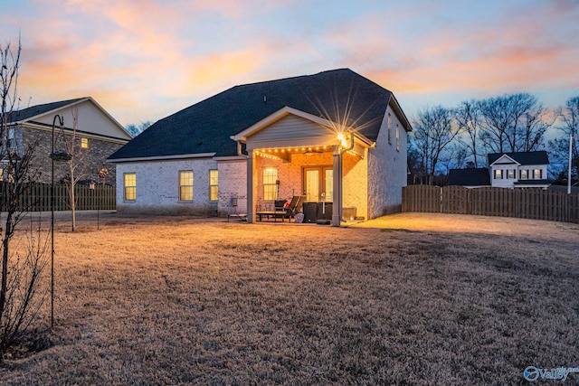 back of property featuring a lawn, fence, a patio, and french doors