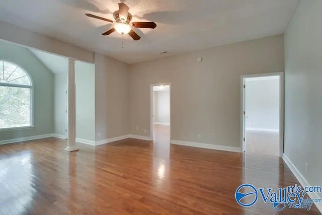 spare room featuring ceiling fan, wood-type flooring, lofted ceiling, and ornate columns