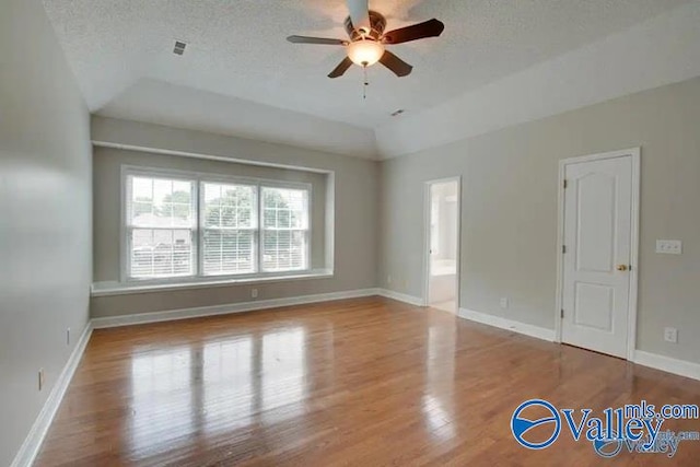 unfurnished room featuring lofted ceiling, ceiling fan, a textured ceiling, and light hardwood / wood-style flooring