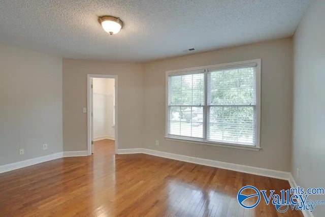 unfurnished room with hardwood / wood-style flooring and a textured ceiling