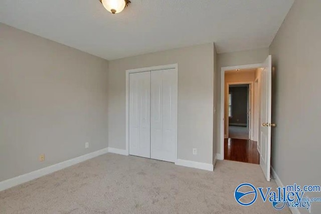 unfurnished bedroom with light carpet and a closet