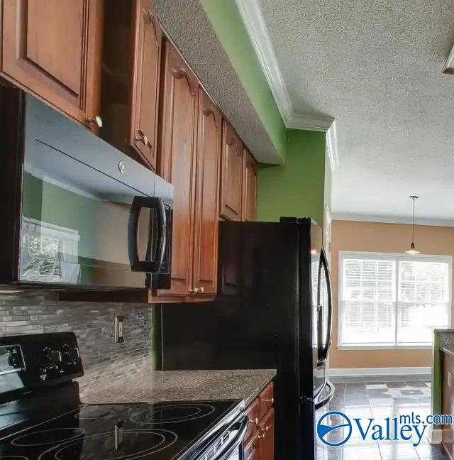 kitchen with tasteful backsplash, black appliances, crown molding, a textured ceiling, and dark stone counters