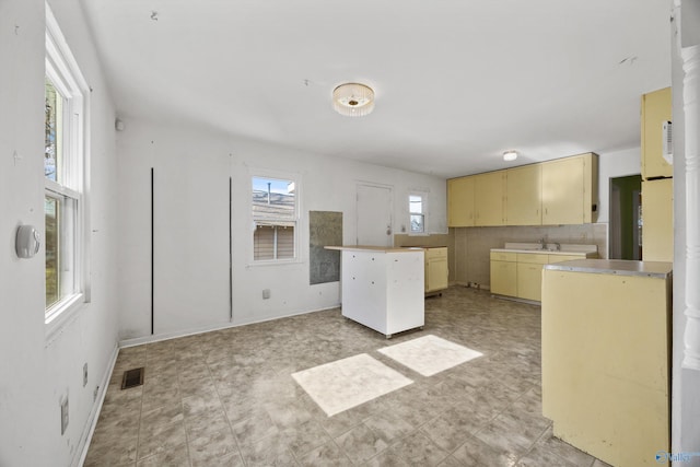 kitchen with cream cabinets, a center island, and sink