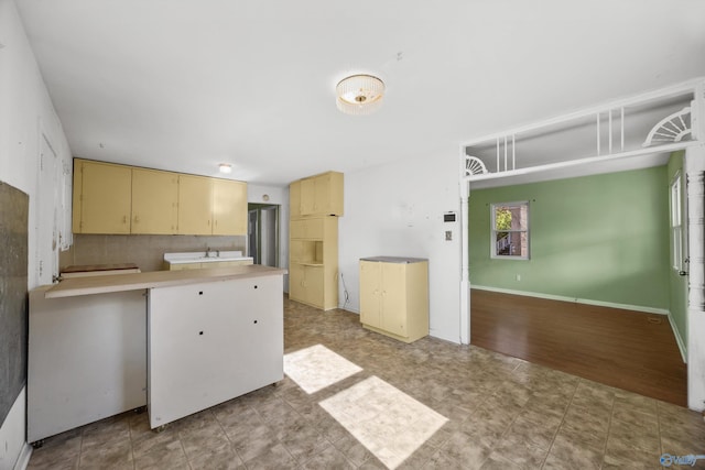 kitchen featuring light hardwood / wood-style floors, kitchen peninsula, sink, and tasteful backsplash