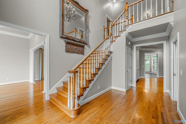 stairs with a high ceiling, hardwood / wood-style flooring, and ornamental molding