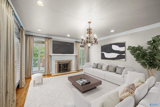 living room with light wood-type flooring, an inviting chandelier, and ornamental molding