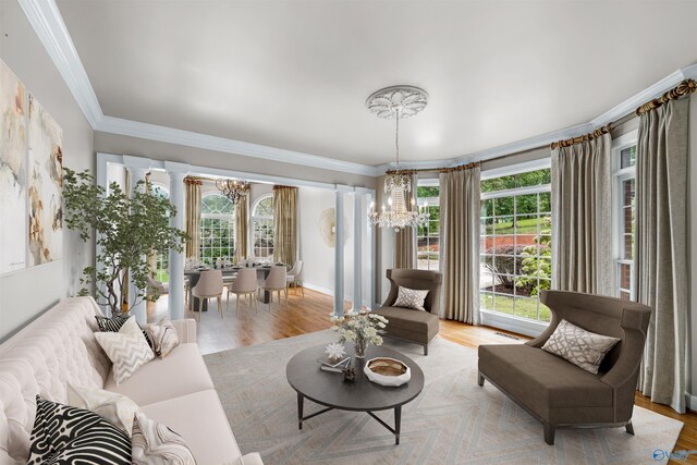 living room with crown molding, light hardwood / wood-style flooring, and an inviting chandelier