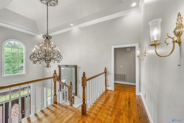 hallway with an inviting chandelier, ornamental molding, and hardwood / wood-style flooring