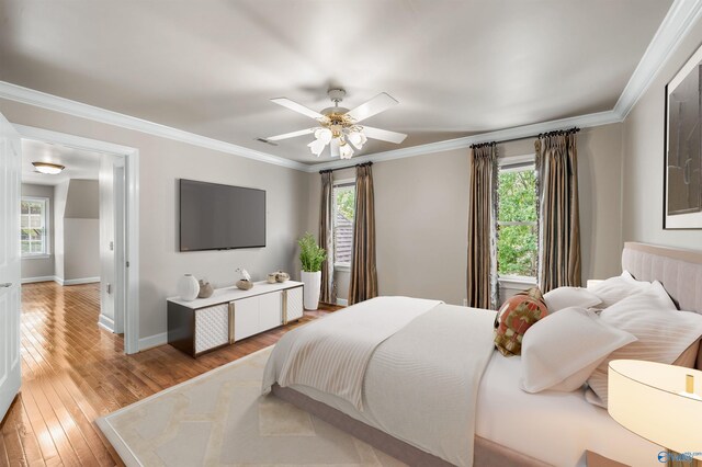 bedroom featuring light wood-type flooring, ornamental molding, and ceiling fan