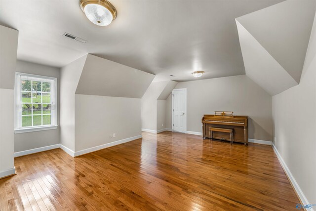 additional living space with hardwood / wood-style floors and vaulted ceiling