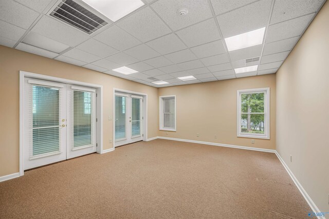 spare room featuring carpet floors, a drop ceiling, and french doors