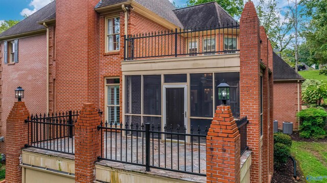 rear view of property featuring a sunroom, a balcony, and central air condition unit