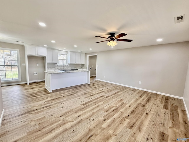 kitchen featuring light stone counters, ceiling fan, light hardwood / wood-style flooring, and white cabinets