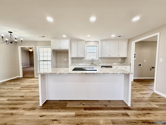 kitchen with light stone countertops, white cabinets, and a kitchen island