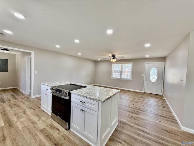 kitchen featuring stainless steel electric range oven, white cabinetry, ceiling fan, light hardwood / wood-style floors, and light stone countertops