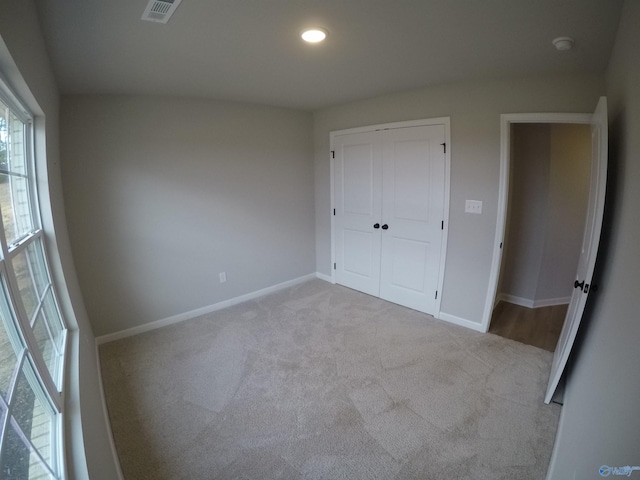 unfurnished bedroom with light carpet and a closet