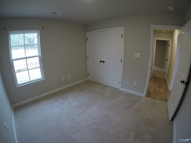 unfurnished bedroom with light carpet and a closet