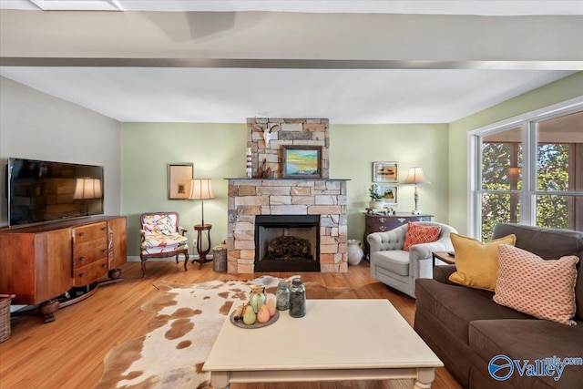 living room with wood-type flooring and a stone fireplace