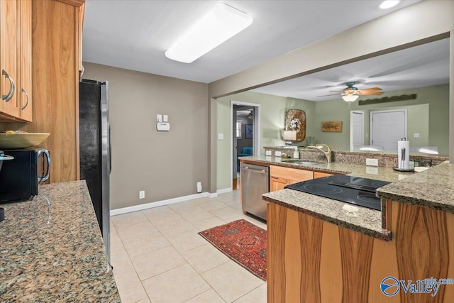 kitchen with kitchen peninsula, ceiling fan, stainless steel appliances, stone countertops, and sink