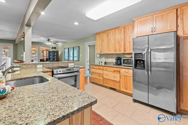 kitchen featuring ceiling fan, decorative backsplash, sink, light stone countertops, and stainless steel appliances