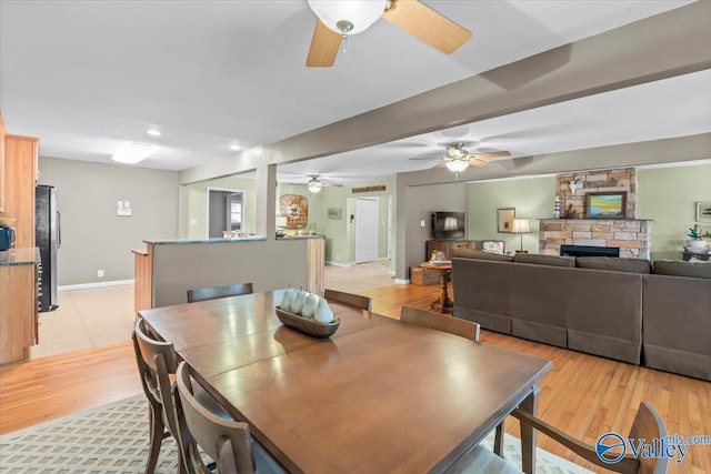 dining area with a stone fireplace and light hardwood / wood-style flooring