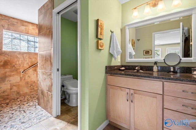 bathroom featuring toilet, vanity, and tiled shower