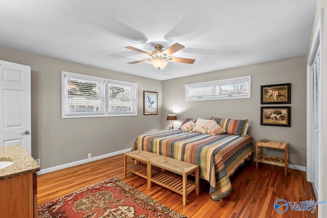 bedroom featuring ceiling fan, wood-type flooring, a closet, and multiple windows