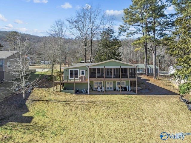 back of house featuring a patio area, a wooden deck, a lawn, and a sunroom