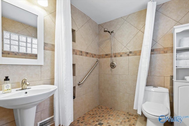 bathroom featuring toilet, tile walls, and walk in shower