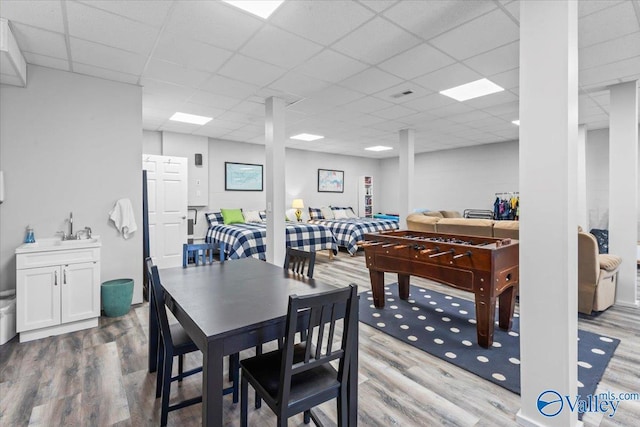 dining area with a drop ceiling, light hardwood / wood-style flooring, and sink