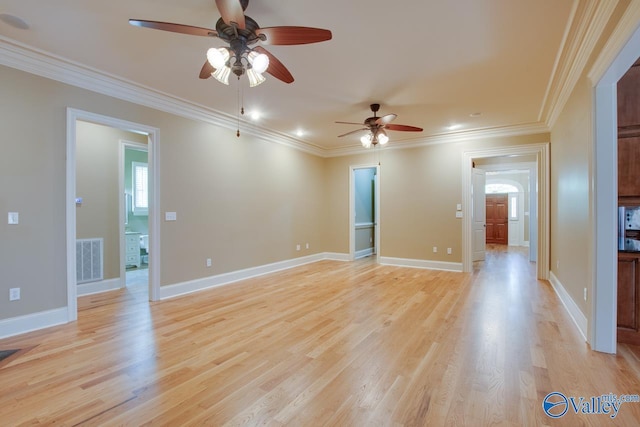 empty room with visible vents, crown molding, light wood-style flooring, and baseboards