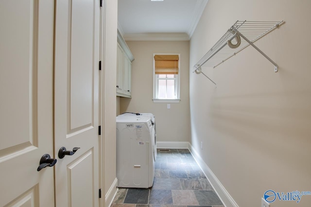 laundry room featuring crown molding, cabinet space, stone finish floor, washer and dryer, and baseboards