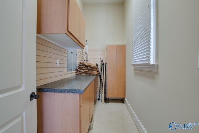 interior space featuring dark countertops, baseboards, and light brown cabinetry