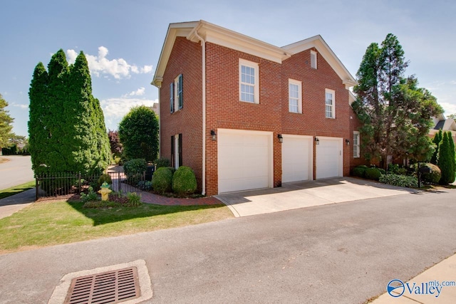 view of side of home featuring a garage, fence, concrete driveway, and brick siding