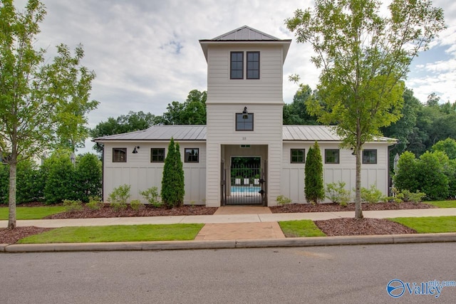 modern inspired farmhouse featuring a standing seam roof, metal roof, board and batten siding, and a gate