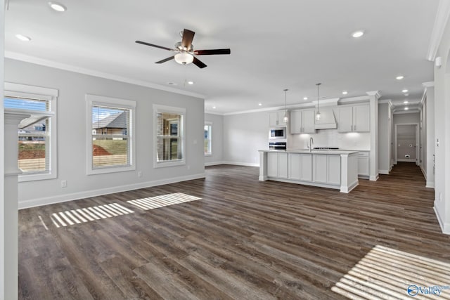 unfurnished living room featuring ceiling fan, sink, crown molding, and dark hardwood / wood-style floors