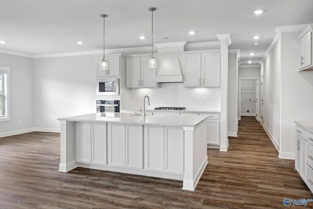 kitchen with a center island with sink, premium range hood, built in microwave, and wall oven