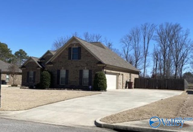 traditional home featuring concrete driveway, fence, and an attached garage