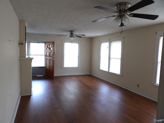 empty room featuring ceiling fan, a healthy amount of sunlight, and dark hardwood / wood-style flooring