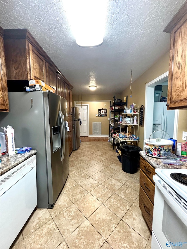 kitchen with white appliances, light tile patterned flooring, and a textured ceiling