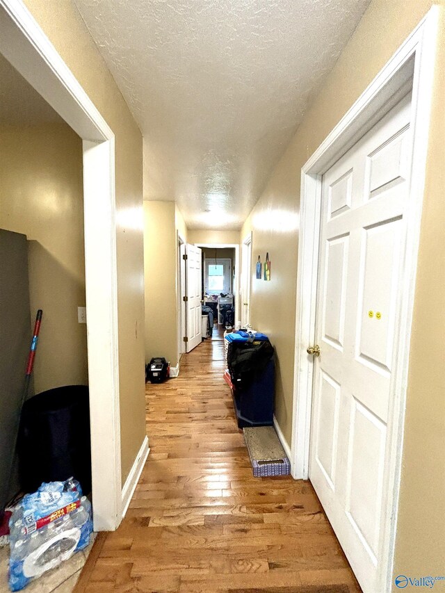 hall featuring a textured ceiling and light wood-type flooring