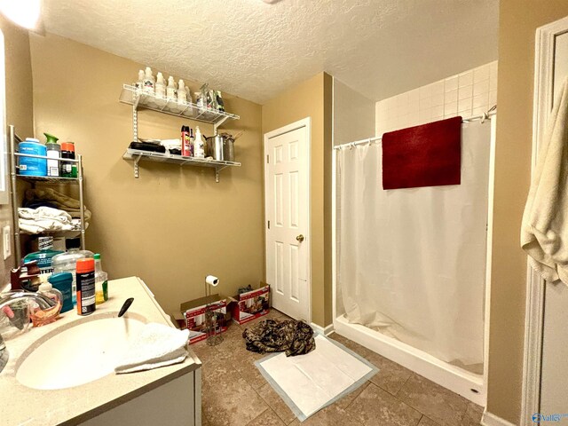 bathroom with tile patterned floors, vanity, a textured ceiling, and curtained shower