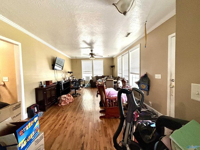 exercise area with ceiling fan, a textured ceiling, crown molding, and wood-type flooring