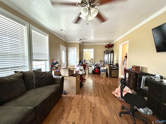 living room with ceiling fan, a textured ceiling, ornamental molding, and hardwood / wood-style flooring