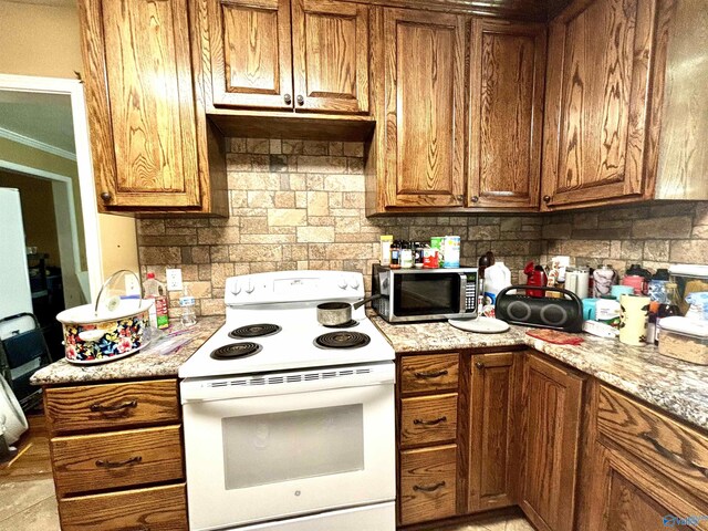 kitchen featuring light stone countertops, backsplash, and white range with electric stovetop