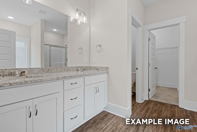 bathroom with wood-type flooring, toilet, a shower with door, and vanity